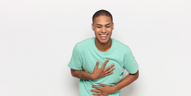 Joven negro riéndose a carcajadas de una broma hilarante, sintiéndose feliz y alegre, divirtiéndose