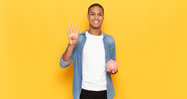 Joven negro sonriendo y mirando amistosamente, mostrando el número cuatro o cuarto con la mano hacia adelante, contando hacia atrás