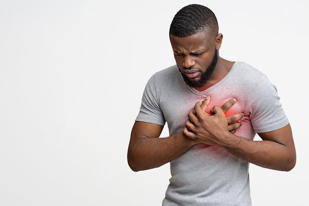 Joven negro teniendo un ataque al corazón sosteniendo su pecho