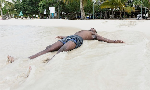 Joven negro tirado en la arena