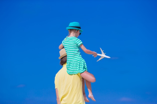 Joven y niña con miniatura de avión en la playa