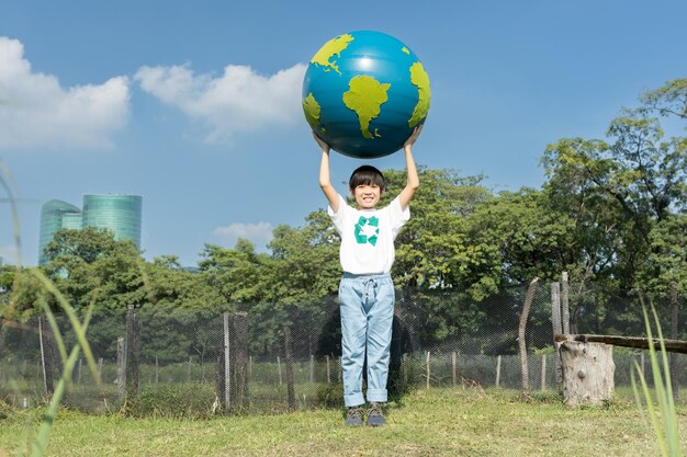 Joven niño asiático sosteniendo el globo del planeta Tierra en el fondo del parque natural Gyre