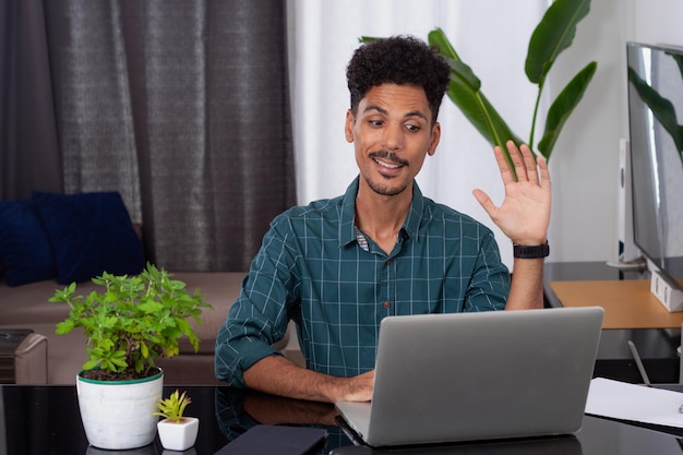 Joven nómada en una reunión de teletrabajo en un escritorio con una computadora portátil