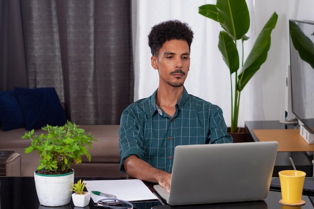 Joven nómada en una reunión de teletrabajo en un escritorio con una computadora portátil