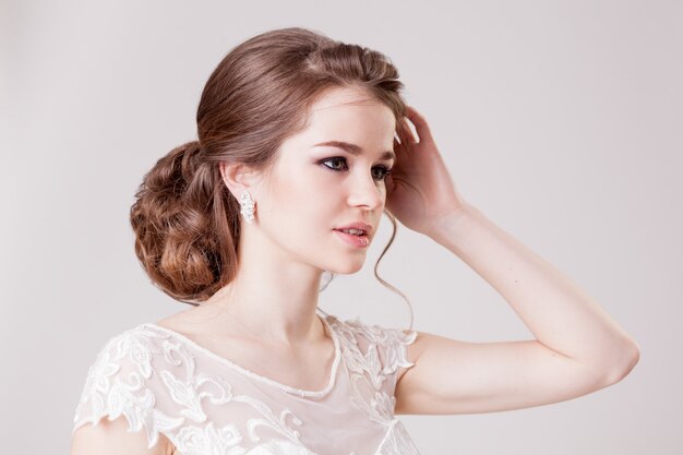 Joven novia con un hermoso peinado y maquillaje posando en el estudio.