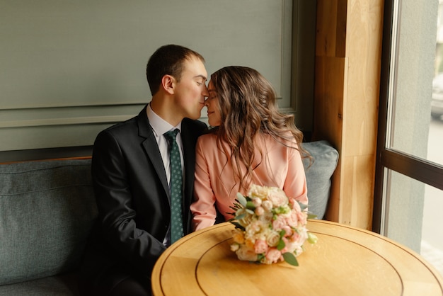 Foto joven novia y el novio en un café. el esposo y la esposa se toman de las manos.