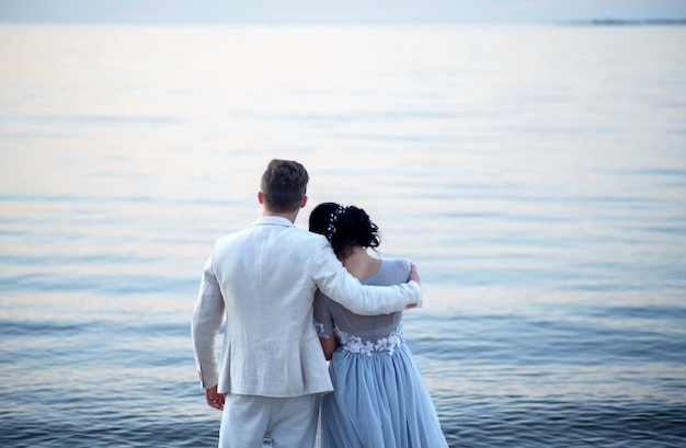Joven novia y el novio cerca del mar en la playa al atardecer