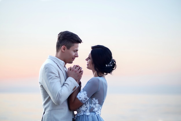 Joven novia y el novio cerca del mar en la playa al atardecer