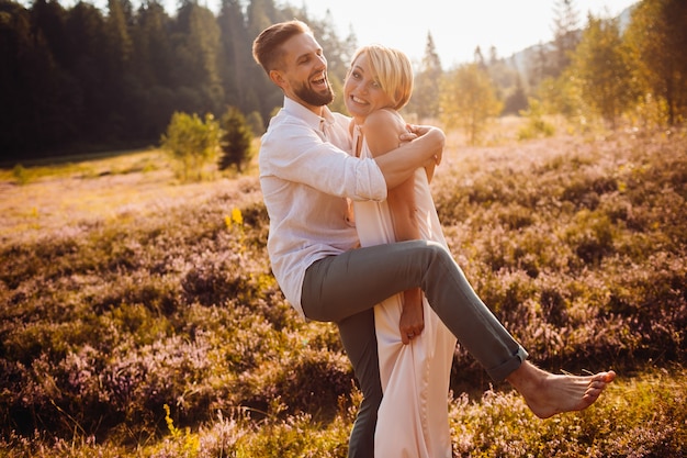 Joven novia y el novio se ven divertidos posando en el campo