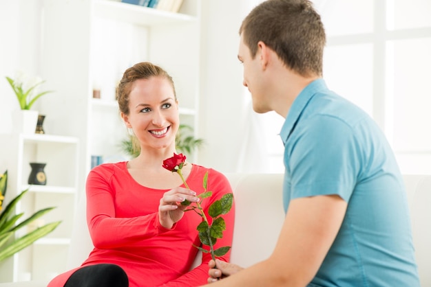 Joven novio dando rosa a su hermosa novia