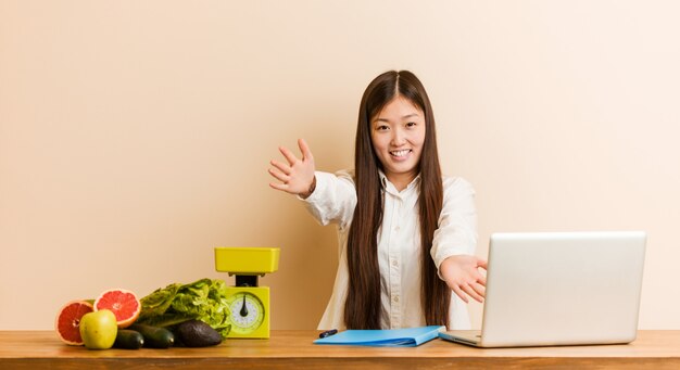 Joven nutricionista china que trabaja con su computadora portátil se siente segura dando un abrazo