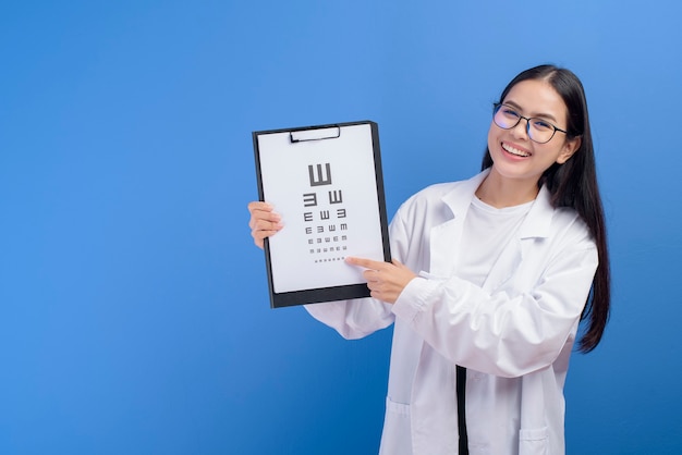 Una joven oftalmóloga con gafas sosteniendo un gráfico optométrico sobre azul, concepto de salud