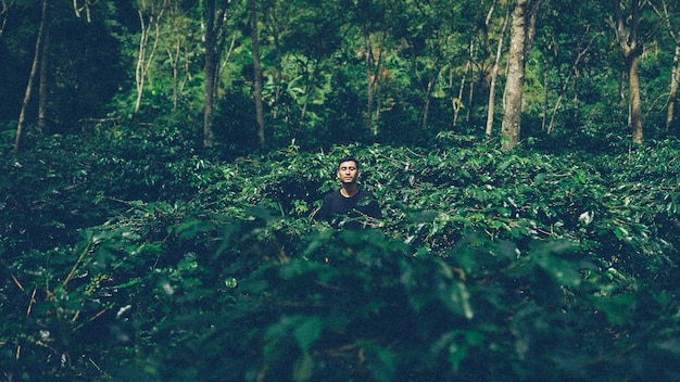 Foto joven con los ojos cerrados de pie en medio de las plantas