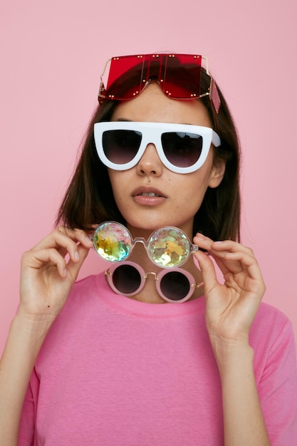 Una joven optimista con muchas gafas en la cara con una camiseta rosa de fondo aislado