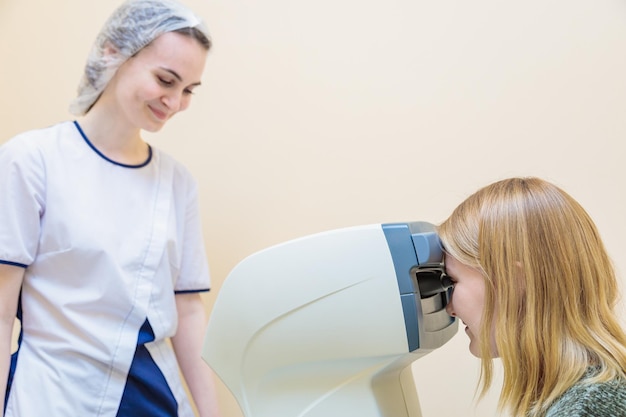 Una joven optometrista examina los ojos de un paciente usando un equipo moderno especial