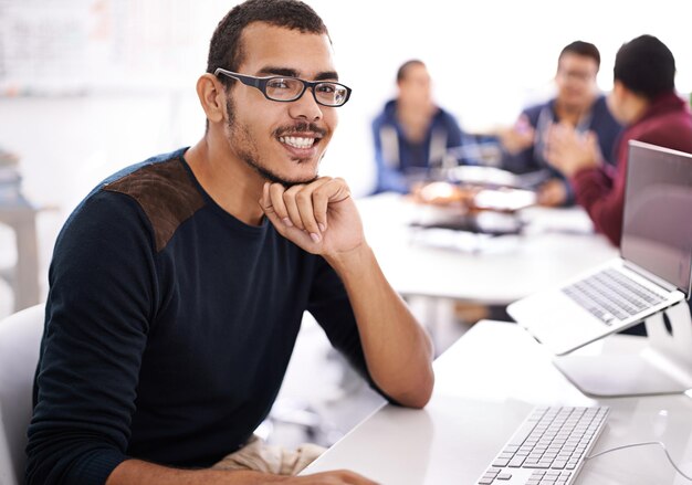 Joven ordenador y retrato en el espacio de trabajo para el desarrollo web programación o tecnología de la información Trabajador programador de negocios o diseñador en línea con gafas para la planificación y el proyecto de puesta en marcha