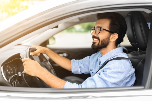 Foto joven oriental alegre en un gerente casual conduciendo un coche blanco