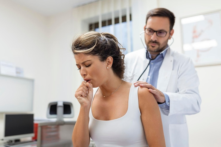 Una joven paciente de la clínica sufrió de neumonía. Está tosendo. El médico escucha el silbido en los pulmones con un estetoscopio.