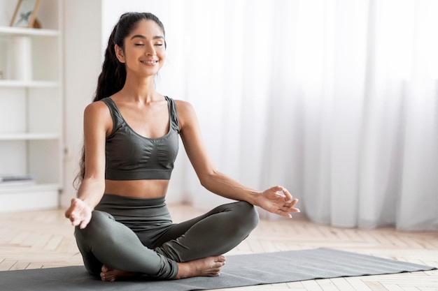 Foto joven y pacífica mujer oriental meditando en casa