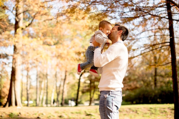 Joven padre y bebé en el parque de otoño