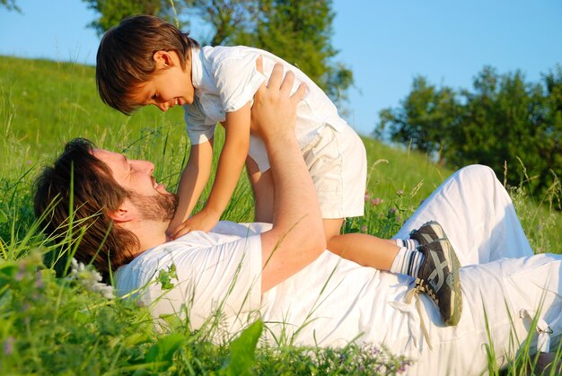 Joven padre en blanco con el niño en el hermoso prado