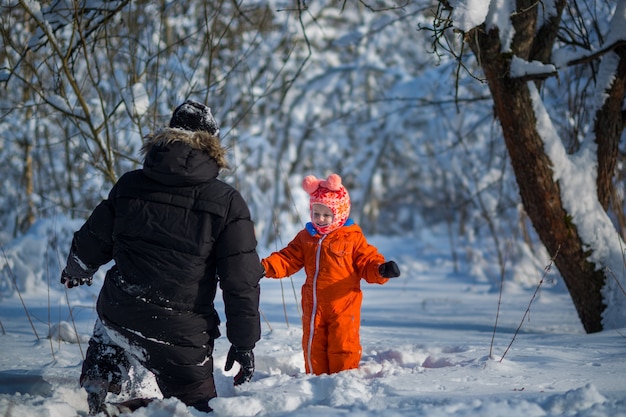 Joven padre e hija en vacaciones de invierno en el bosque de nieve.