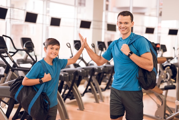 Foto joven padre e hijo cerca de cintas de correr en un moderno gimnasio