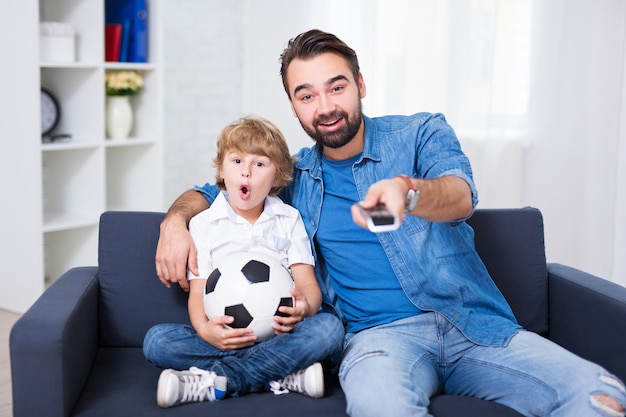 Joven padre e hijo viendo fútbol en tv