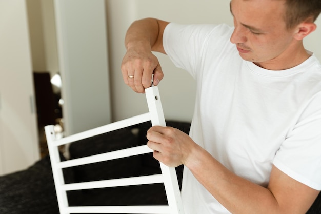 un joven padre está montando una cuna concepto de preparar el hogar para el nacimiento de un niño paternidad