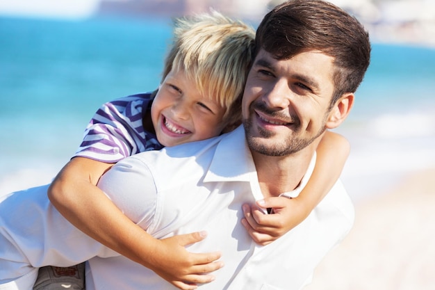 Joven padre con hijo en el fondo de la playa