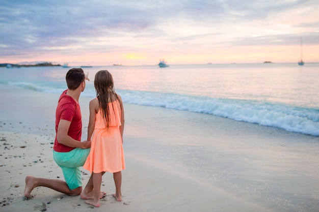 Joven padre con su hijo pequeño mirando el atardecer en las playas exóticas