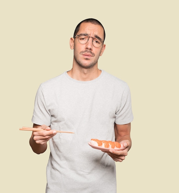 Joven con palillos para comer sushi