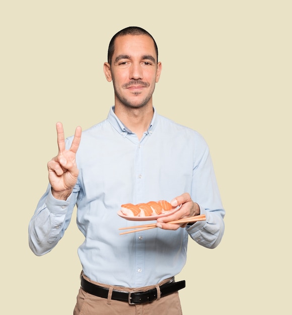 Joven con palillos para comer sushi