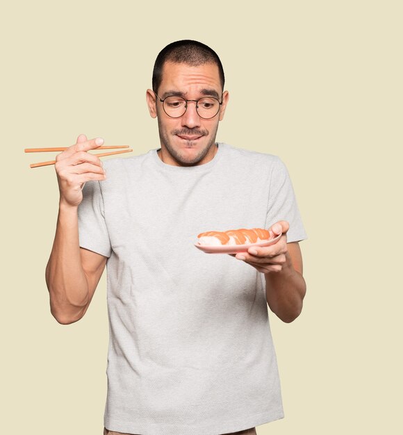 Joven con palillos para comer sushi