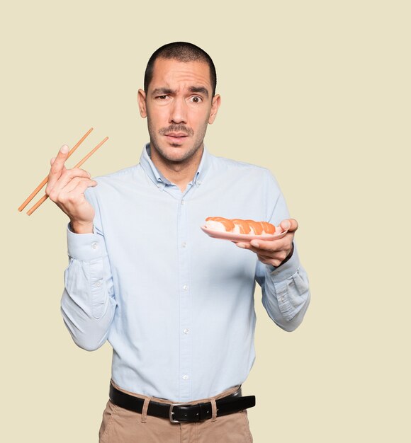 Joven con palillos para comer sushi