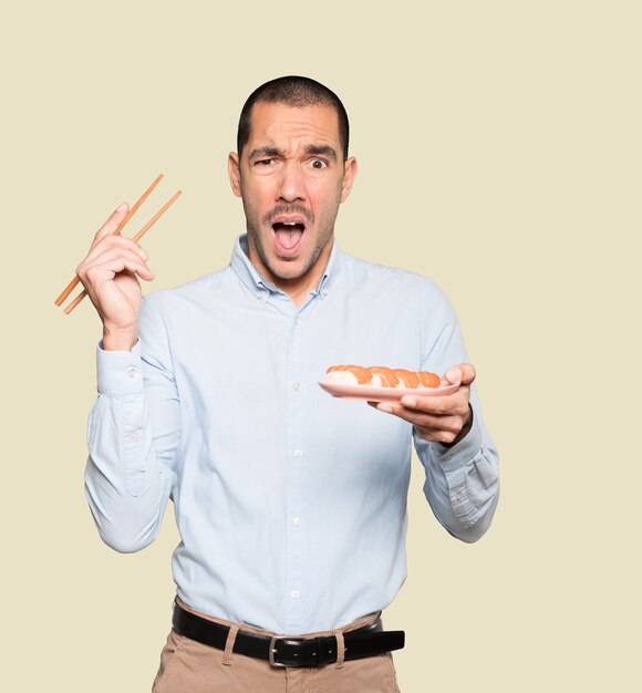 Joven con palillos para comer sushi