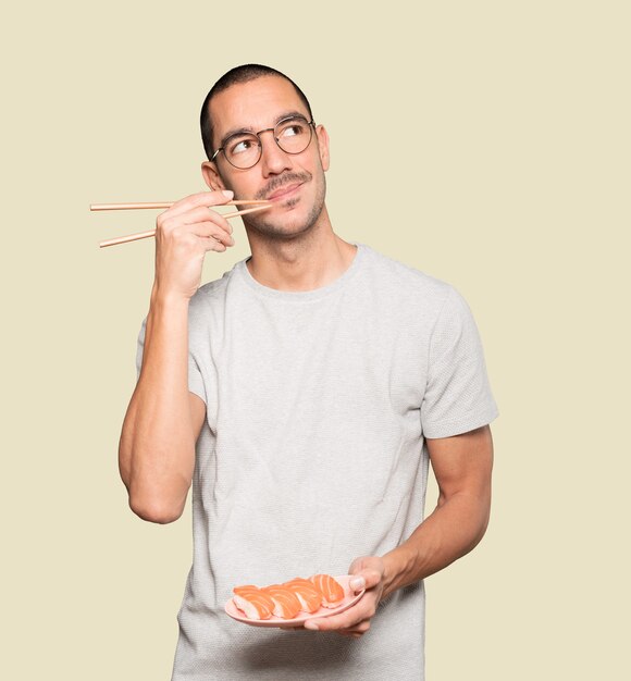 Joven con palillos para comer sushi