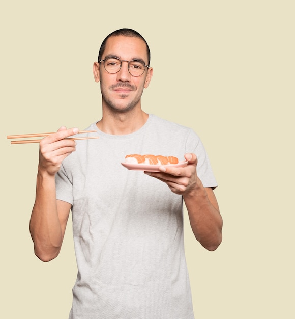 Joven con palillos para comer sushi