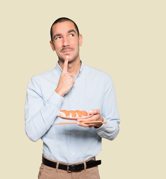 Joven con palillos para comer sushi