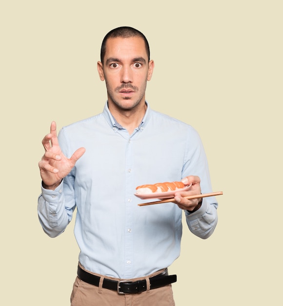 Joven con palillos para comer sushi