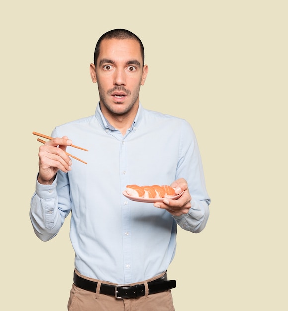 Joven con palillos para comer sushi