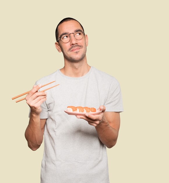 Joven con palillos para comer sushi