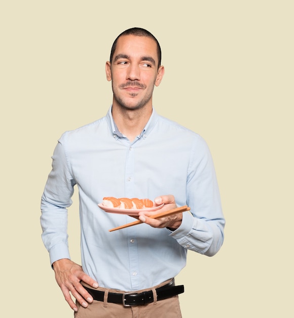 Joven con palillos para comer sushi