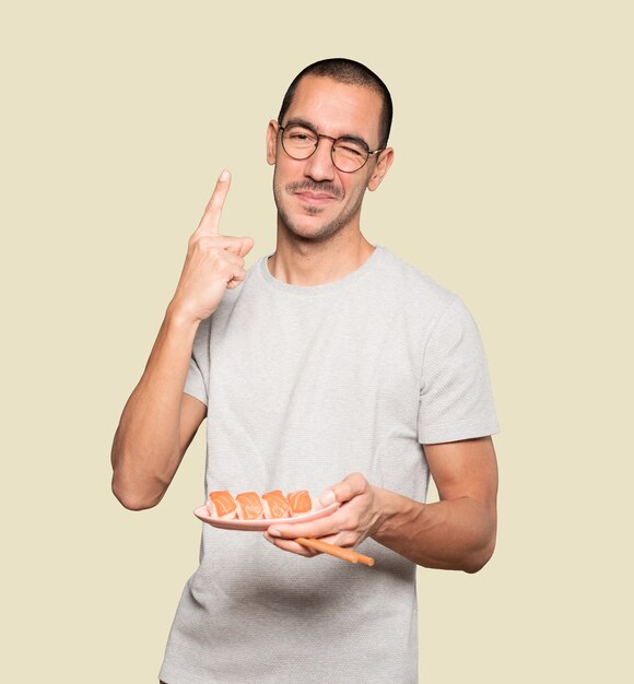 Joven con palillos para comer sushi