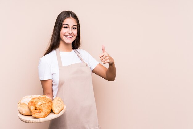 Joven panadero caucásico aislado sonriendo y levantando el pulgar