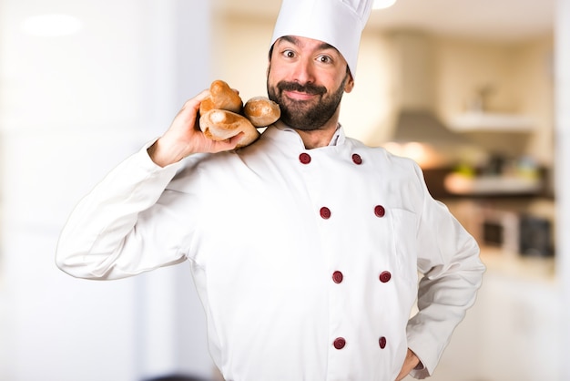 Joven panadero sosteniendo un poco de pan en la cocina