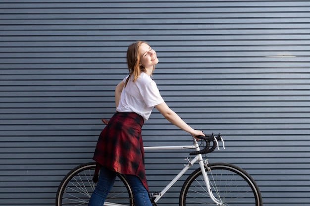 joven parado con una bicicleta blanca