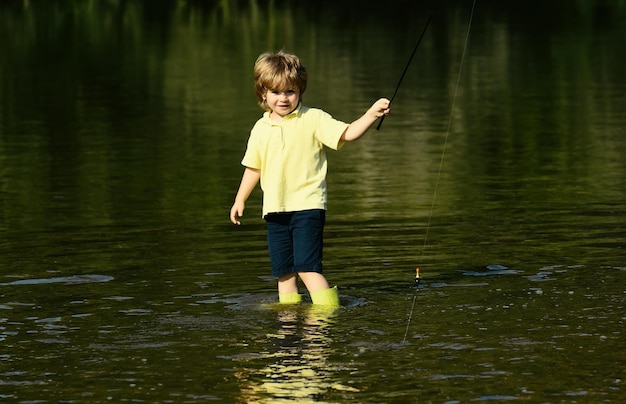 Joven parado en el río con caña de pescar en un día soleado chico lindo está pescando en el río en el su