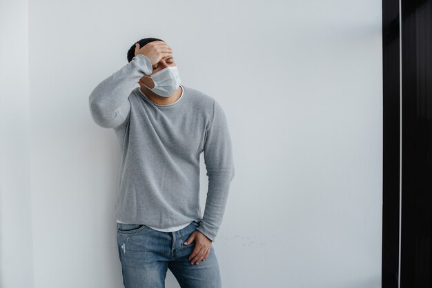 Foto un joven parado sobre un fondo gris con una máscara durante una cuarentena con espacio libre.