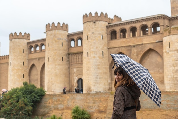 Una joven con paraguas en la Aljafería Palacio de los reyes Hudie de Saraqusta en la ciudad de Zaragoza, junto al río Ebro en Aragón. España